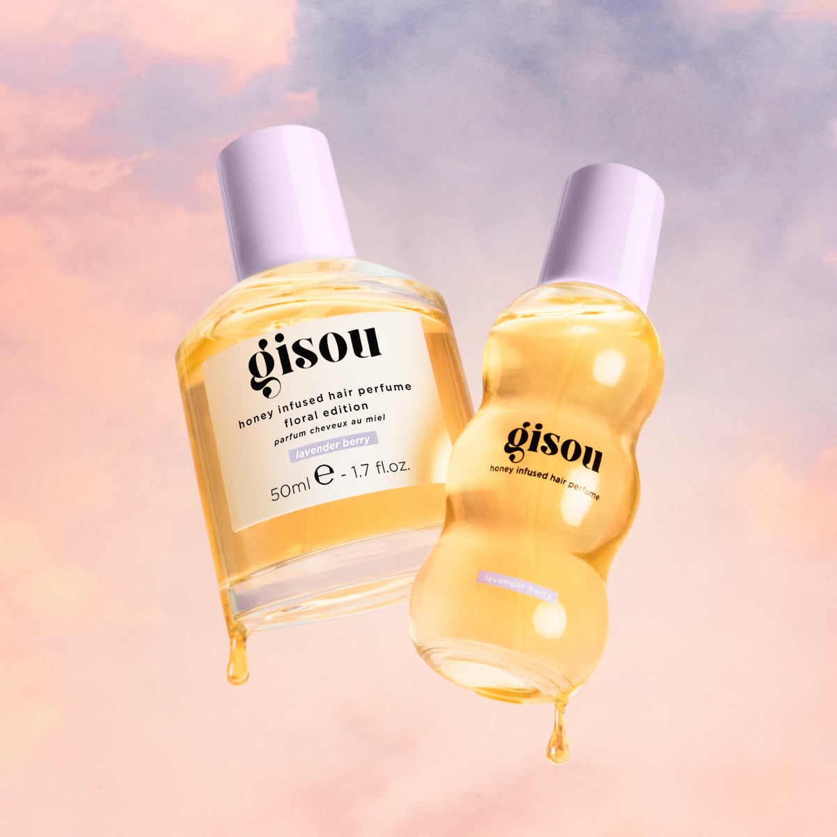 Honey dripping from two hair perfume bottles with pastel clouds in the background.