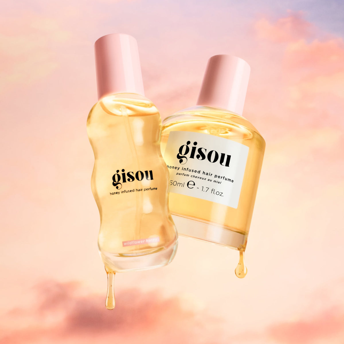 Honey dripping from two hair perfume bottles with pink clouds in the background.
