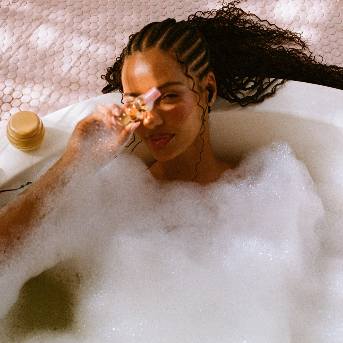 Model holding the mini hair perfume in a bathtub.