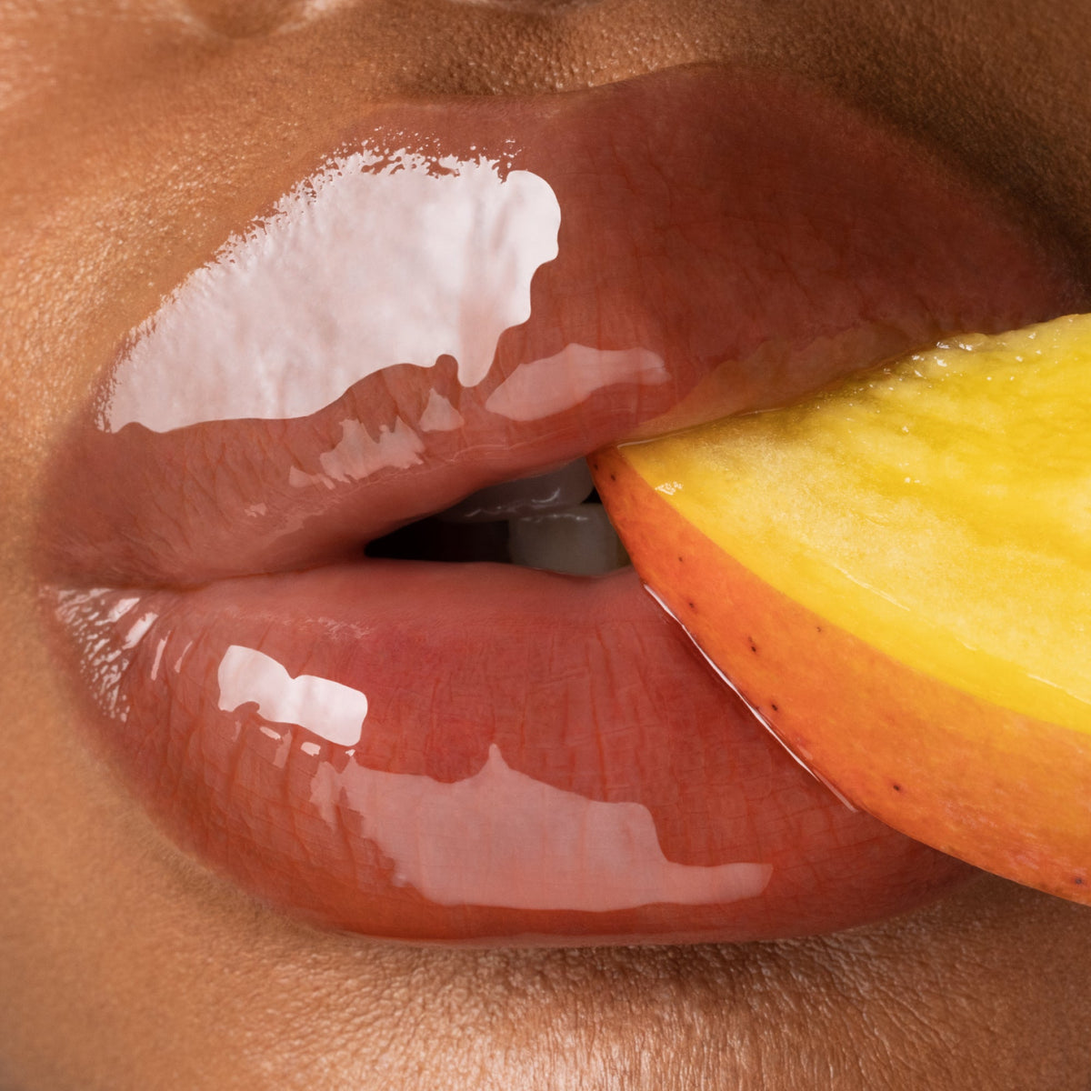 Close up of glossy lips biting a mango.