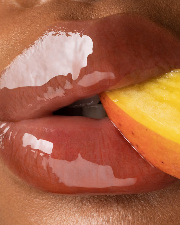 Close up of glossy lips biting a mango.