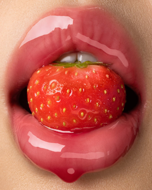 Glossy lips holding a strawberry.