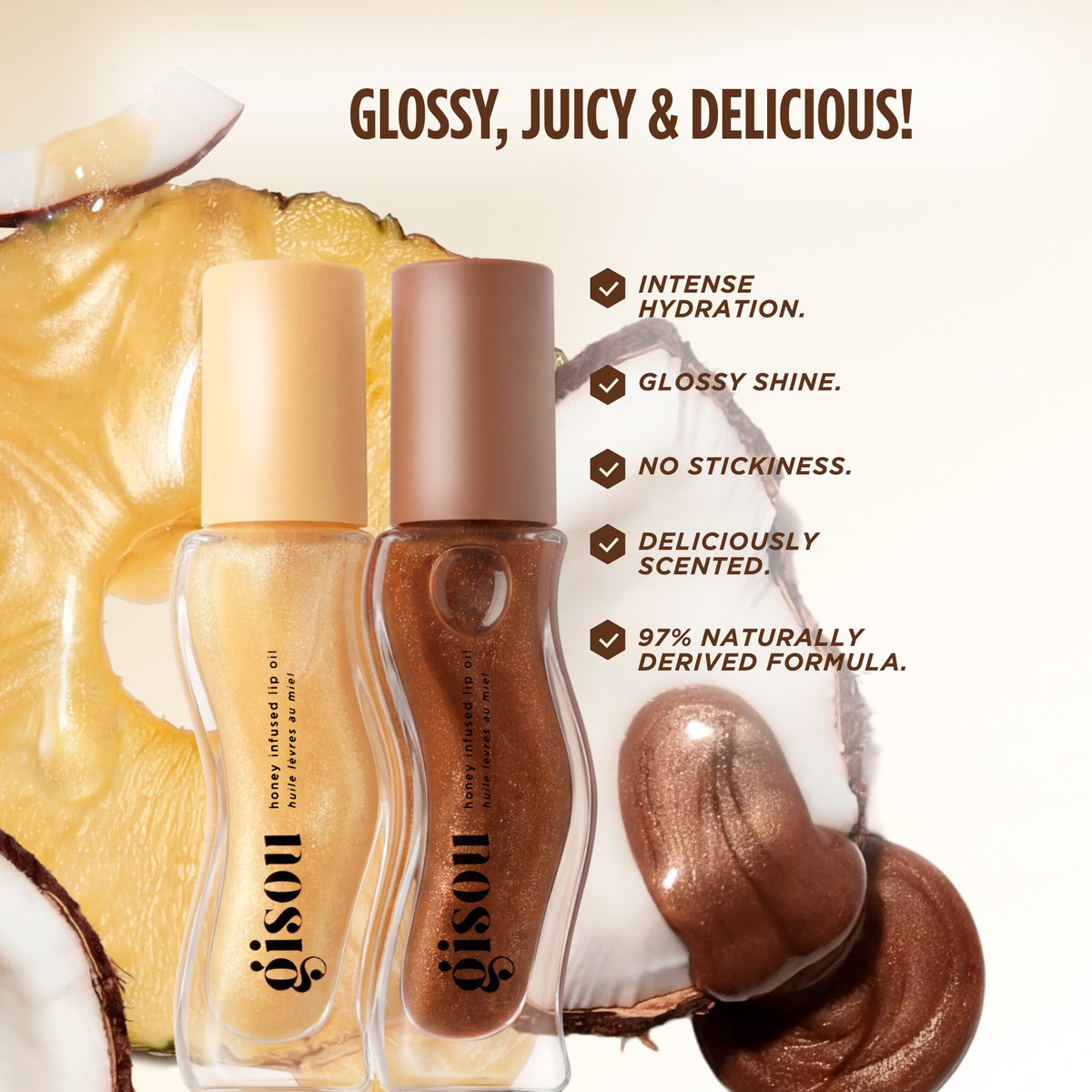 Glossy Juicy & Delicious visual showing two Gisou Honey Infused Lip Oils: Pineapple Pout and Coco-Cacao, placed in front of pineapple and coconut, with claims of intense hydration, glossy shine, no stickiness, delicious scent, and 97% naturally derived formula.
