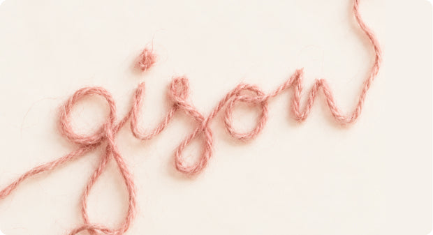 Gisou logo spelled in pink yarn on a cream background