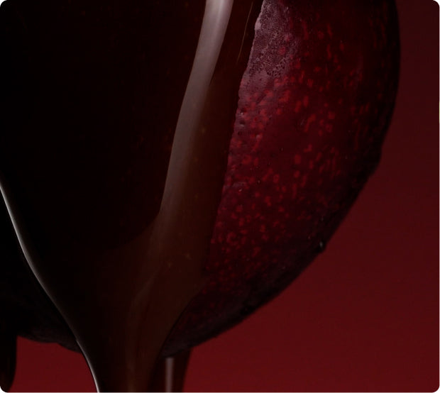 Melted chocolate dripping over a dark cherry