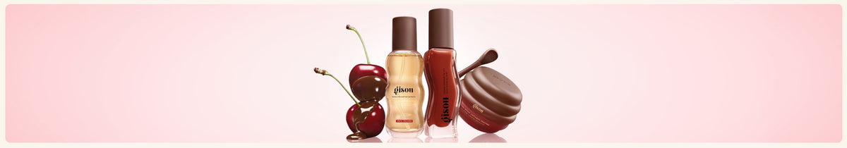 The whole line up of the Cherry Choco fall collection, including hair perfume, lip oil, and lip mask next to cherries in chocolate.