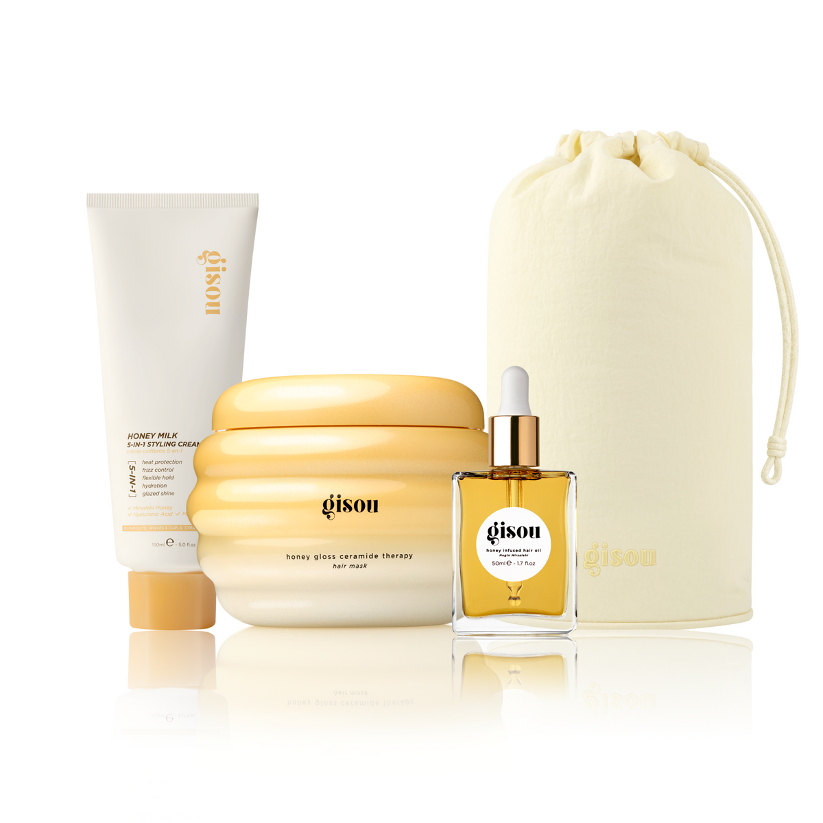 Gisou Honey Milk 5-in-1 Styling Cream, Honey Gloss Ceramide Therapy Hair Mask, Honey Infused Hair Oil, and a Gisou Honey Glow Hair Towel pouch grouped together on white.