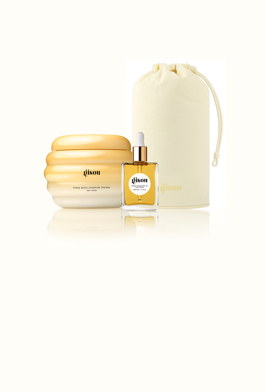 Gisou Honey Gloss Ceramide Therapy Hair Mask, Gisou Honey Infused Hair Oil, and a Gisou Honey Glow Hair Towel pouch grouped together on white.