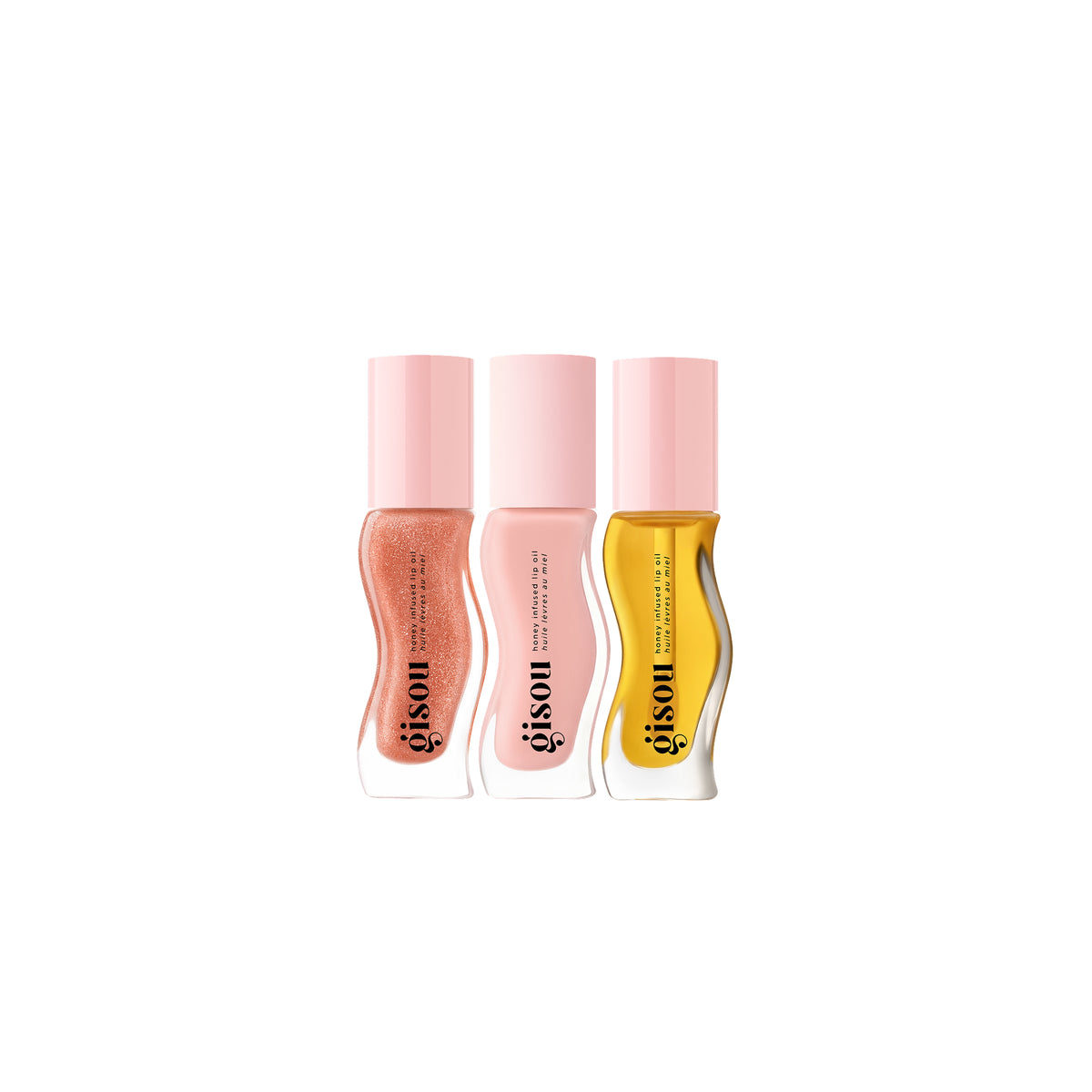 Three Mini Honey Infused Lip Oil bottles in warm tones: one soft peach-pink, one light milky pink, and one clear golden yellow, each with a glossy finish.