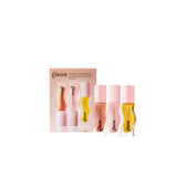 Mini Lip Collectibles set with three lip oils in soft peach-pink, pale pink, and transparent honey-gold yellow, displayed in front of a matching pastel pink box.