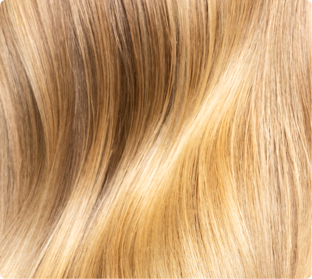 Close-up of glossy, healthy blonde balayage hair with soft waves.