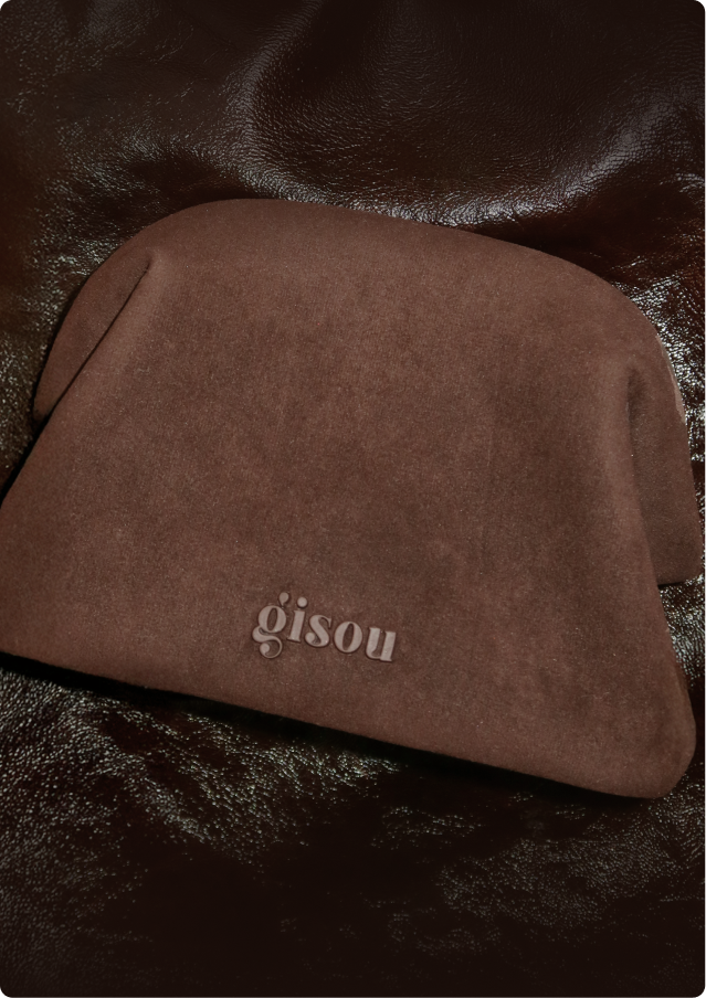 A close-up shot of Gisou on a Choco Suede Pouch.