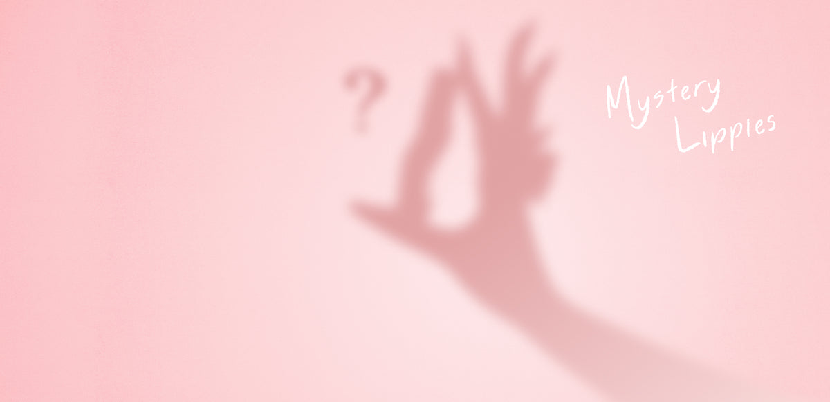 Mystery Lippies: shadow of a hand holding a Gisou lip oil with a question mark on pink