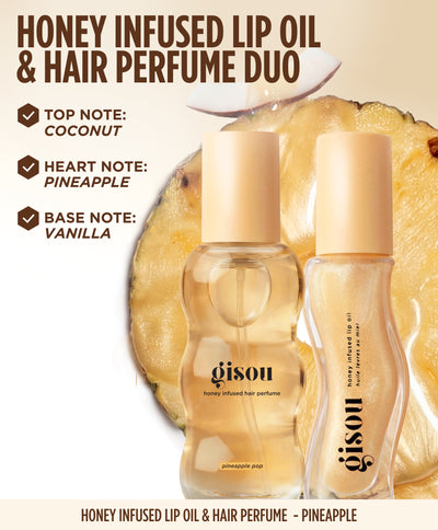 Gisou Honey Infused Lip Oil and Hair Perfume Duo in the Pineapple collection displayed in front of fresh pineapple. The visual features Pineapple Pop Hair Perfume and Pineapple Pout Lip Oil with tropical fragrance notes including coconut, pineapple and vanilla listed beside the products.
