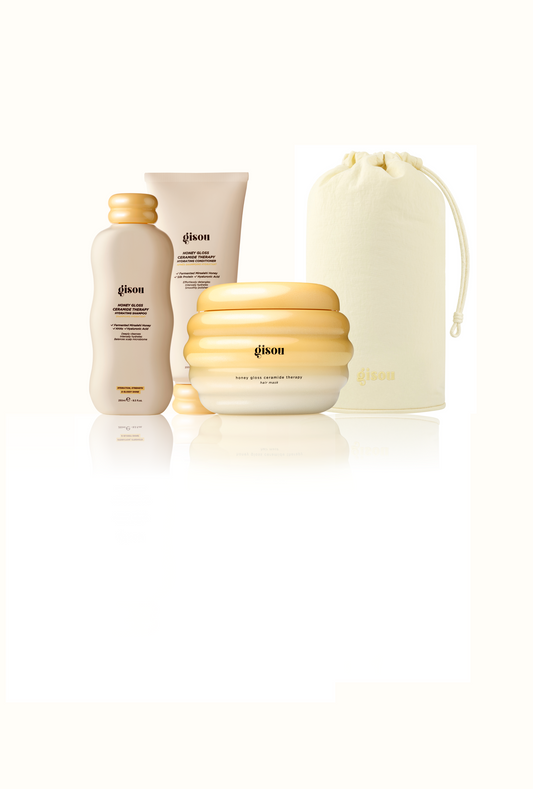 Gisou Honey Gloss Ceramide Therapy Hydrating Shampoo, Hydrating Conditioner, Hair Mask, and a Honey Glow Hair Towel pouch grouped together on white.