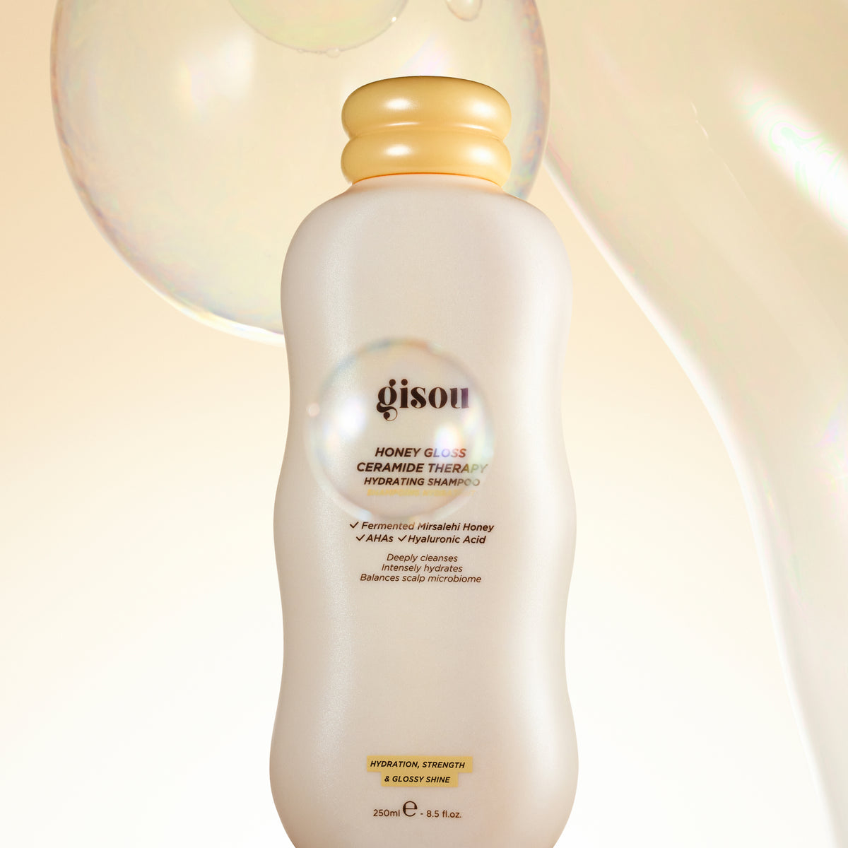 Gisou Honey Gloss Ceramide Therapy Hydrating Shampoo bottle with soft bubble texture background highlighting hydration and glossy shine.