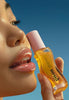 Close-up model holding Honey Infused Lip Oil