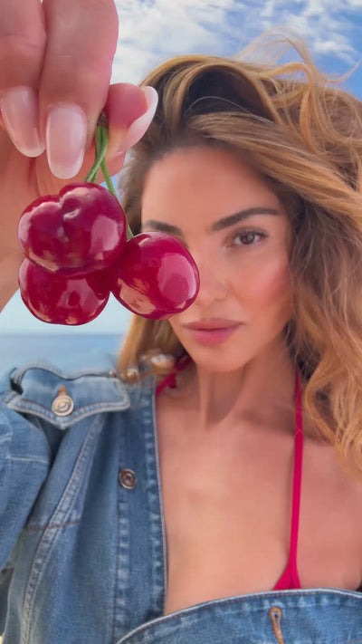 A model applying Hair & Body Mist Glazed Cherry on the beach.